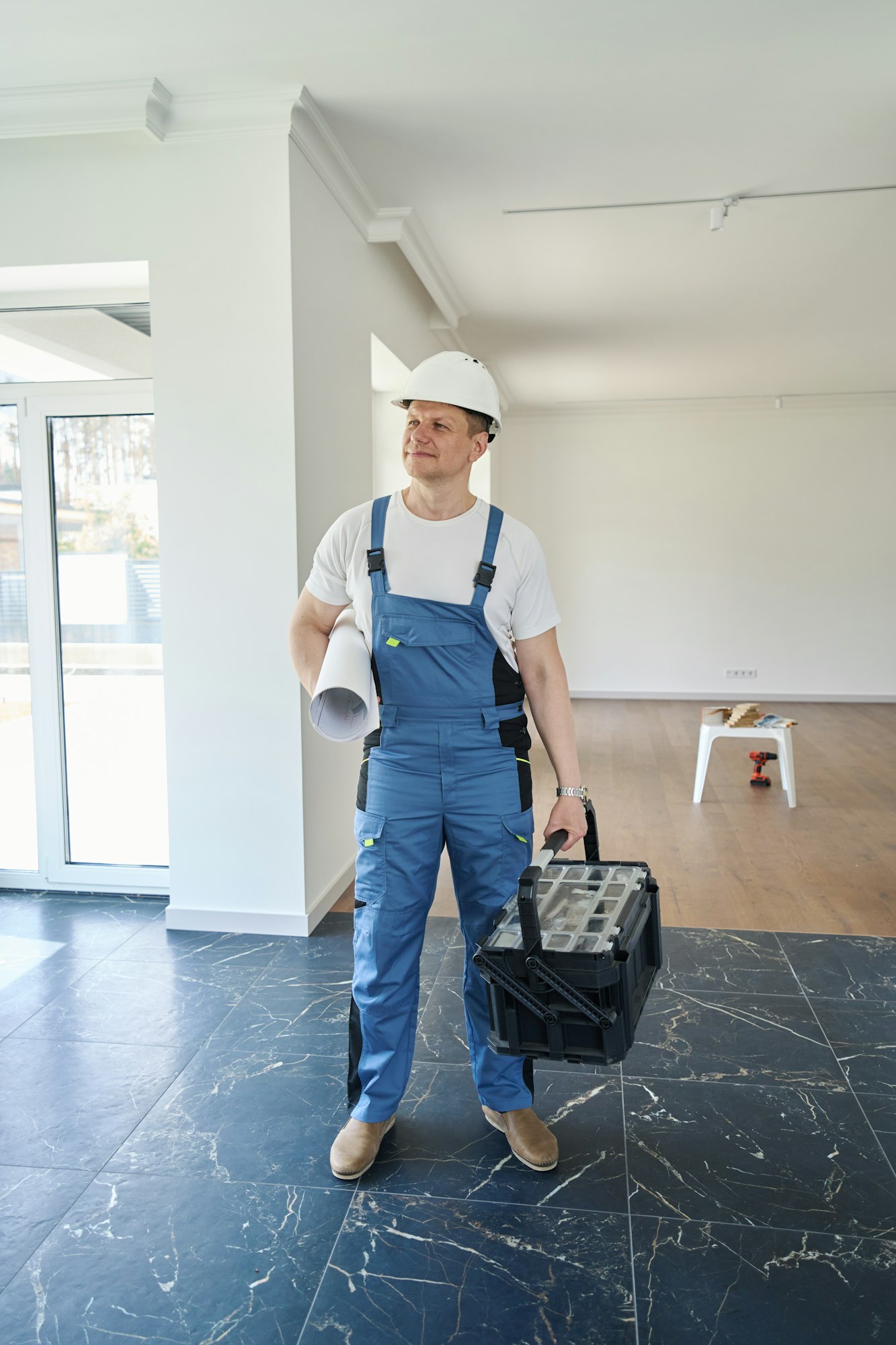 Male worker with blueprint and toolbox in new modern comfortable townhouse